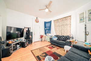 Living room featuring crown molding, ceiling fan, and light wood-type flooring