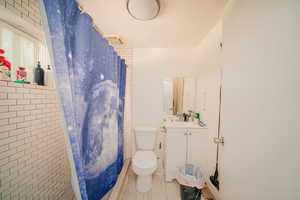 Bathroom with vanity, a textured ceiling, toilet, and tile walls