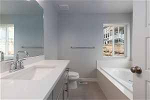 Bathroom featuring a bathing tub, toilet, vanity with extensive cabinet space, and tile flooring