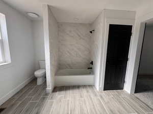 Bathroom with tiled shower / bath and toilet