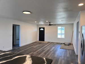 Unfurnished living room featuring ceiling fan and dark hardwood / wood-style flooring