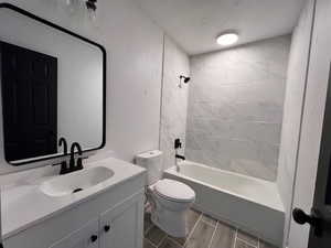 Full bathroom featuring oversized vanity, toilet, and tiled shower / bath combo