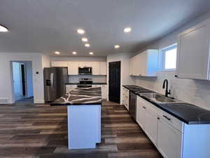 Kitchen featuring stainless steel appliances, sink, dark hardwood / wood-style flooring, and a center island