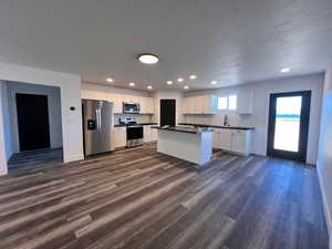 Kitchen featuring a center island, stainless steel appliances, white cabinets, dark hardwood / wood-style floors, and sink