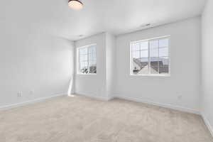 Empty room with a healthy amount of sunlight and light colored carpet