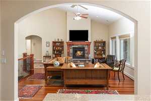 Living room featuring a fireplace, ceiling fan, high vaulted ceiling, and dark hardwood / wood-style flooring