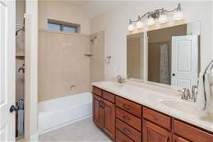 Bathroom featuring shower / bath combination with curtain, double vanity, tile flooring, and vaulted ceiling