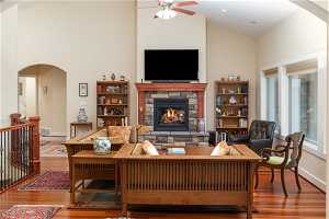 Living room with high vaulted ceiling, wood-type flooring, ceiling fan, and a fireplace