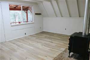 Bonus room featuring lofted ceiling, a wood stove, and light hardwood / wood-style flooring