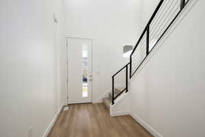 Foyer with light wood-type flooring and a towering ceiling