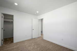 Unfurnished bedroom featuring a closet, carpet, and a spacious closet