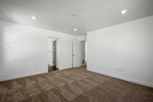 Spare room with a textured ceiling and dark colored carpet