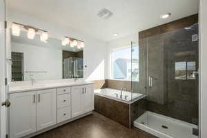 Bathroom featuring tile patterned flooring, vanity, independent shower and bath, and a textured ceiling