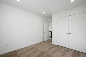 Unfurnished bedroom with light carpet and a closet