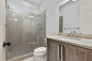 Bathroom featuring vanity, walk in shower, and toilet