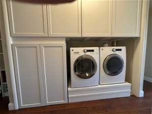 Laundry area with dark hardwood / wood-style flooring, cabinets, and washer and clothes dryer