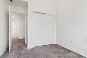 Unfurnished bedroom featuring a closet and light colored carpet