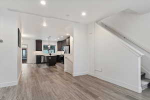 Kitchen featuring a kitchen island, dark brown cabinets, dishwasher, light hardwood / wood-style floors, and decorative light fixtures