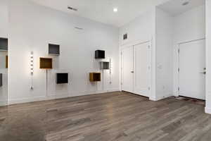 Spare room featuring dark hardwood / wood-style floors and a towering ceiling