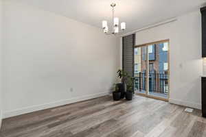 Unfurnished room with a notable chandelier and light wood-type flooring