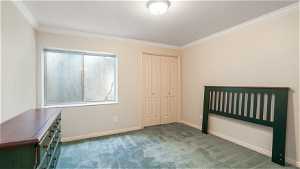 Unfurnished bedroom with dark carpet, ornamental molding, and a closet