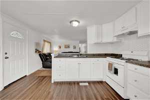 Kitchen featuring sink, white cabinets, white range with gas cooktop, light hardwood / wood-style flooring, and backsplash