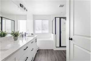Bathroom featuring shower with separate bathtub, hardwood / wood-style floors, and vanity with extensive cabinet space