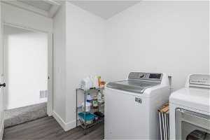Laundry room with dark wood-type flooring and washing machine and clothes dryer