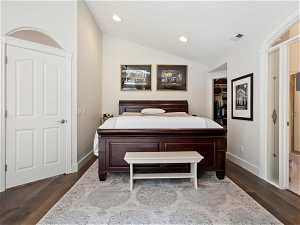 Bedroom with dark hardwood / wood-style floors, a closet, vaulted ceiling, and a walk in closet