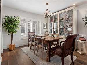 Dining space featuring a chandelier, ornamental molding, and dark hardwood / wood-style flooring