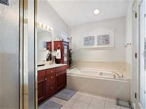 Bathroom with vanity with extensive cabinet space, tile flooring, vaulted ceiling, and a bathing tub