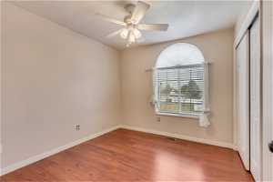 Unfurnished bedroom with a closet, ceiling fan, and dark wood-type flooring