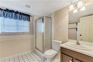 Bathroom featuring a shower with door, tile flooring, a chandelier, toilet, and large vanity
