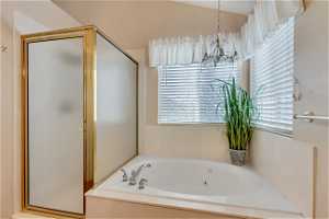 Bathroom with shower with separate bathtub and a notable chandelier