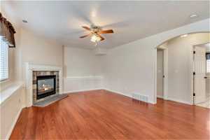 Unfurnished living room with light hardwood / wood-style floors, a tiled fireplace, and ceiling fan