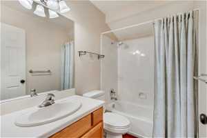 Full bathroom with toilet, vanity, and shower / bath combo with shower curtain