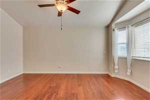 Empty room with lofted ceiling, ceiling fan, and hardwood / wood-style flooring
