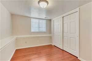 Unfurnished bedroom with light hardwood / wood-style floors, a textured ceiling, and a closet
