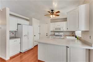 Kitchen featuring white cabinets, ceiling fan, white appliances, and light wood-type flooring