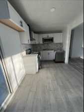 Kitchen featuring white cabinets, range with electric stovetop, tasteful backsplash, and light hardwood / wood-style flooring