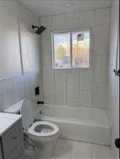 Full bathroom featuring tiled shower / bath, toilet, tile floors, and vanity