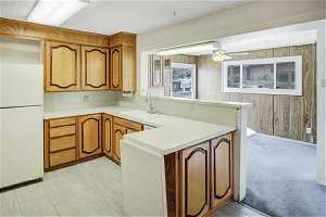 Kitchen featuring kitchen peninsula, white fridge, sink, and light tile floors