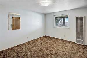 Empty room featuring carpet flooring and a textured ceiling