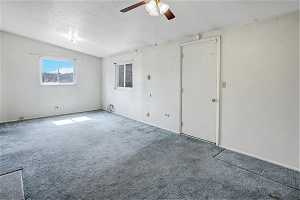 Unfurnished room with a textured ceiling, ceiling fan, vaulted ceiling, and light colored carpet