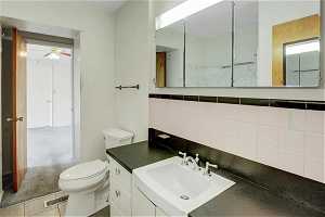 Bathroom featuring ceiling fan, tile walls, tile floors, toilet, and large vanity