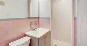 Bathroom with vanity, walk in shower, backsplash, tile walls, and toilet