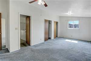 Unfurnished bedroom with light carpet, vaulted ceiling, ceiling fan, and a textured ceiling