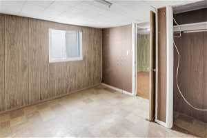 Unfurnished bedroom with wooden walls, a closet, and light tile floors