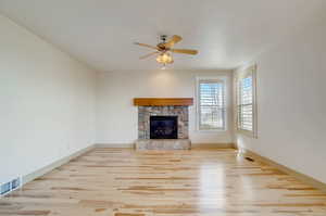 Unfurnished living room with ceiling fan, light wood-type flooring, and a fireplace