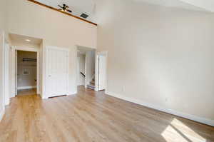 Unfurnished bedroom featuring light hardwood / wood-style floors and a towering ceiling